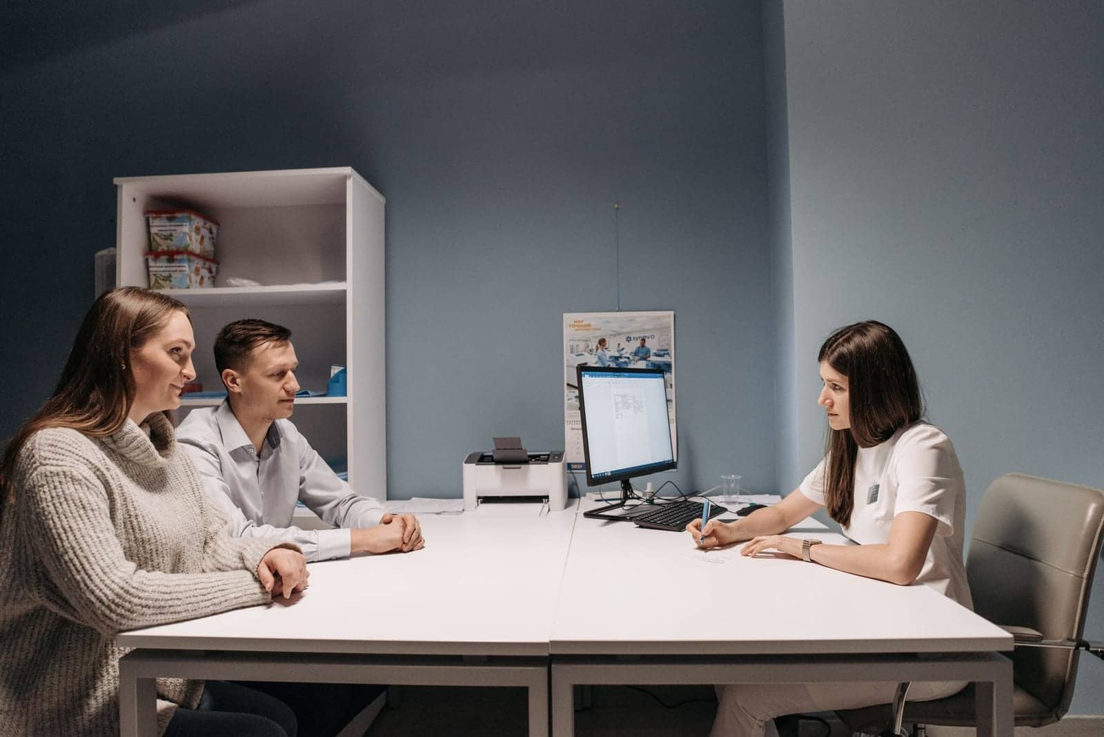 A couple talking with a doctor across a consultation table
