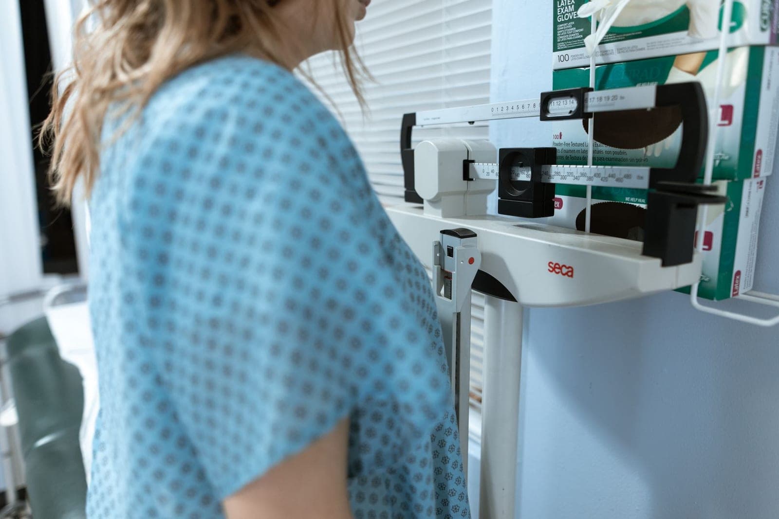 A woman in a hospital gown stepping onto a medical weighing scale